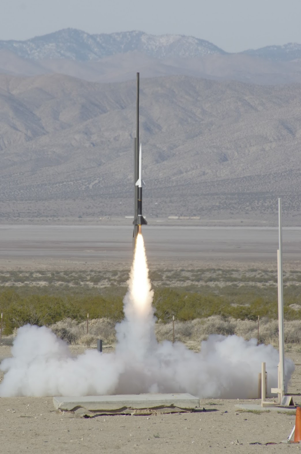 Project Streak lifting off from the rail at FAR, exhaust plume beneath it and the Mojave range behind.
