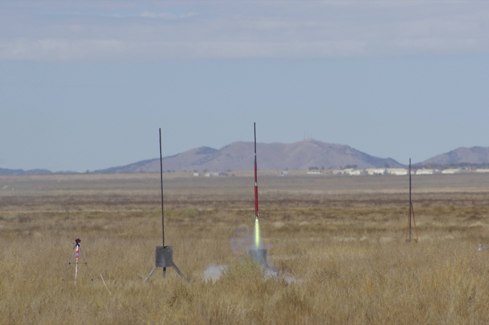 TST climbing off the rail on a bright flame, red and white airframe, with the Frank Hunt range and mountains behind.